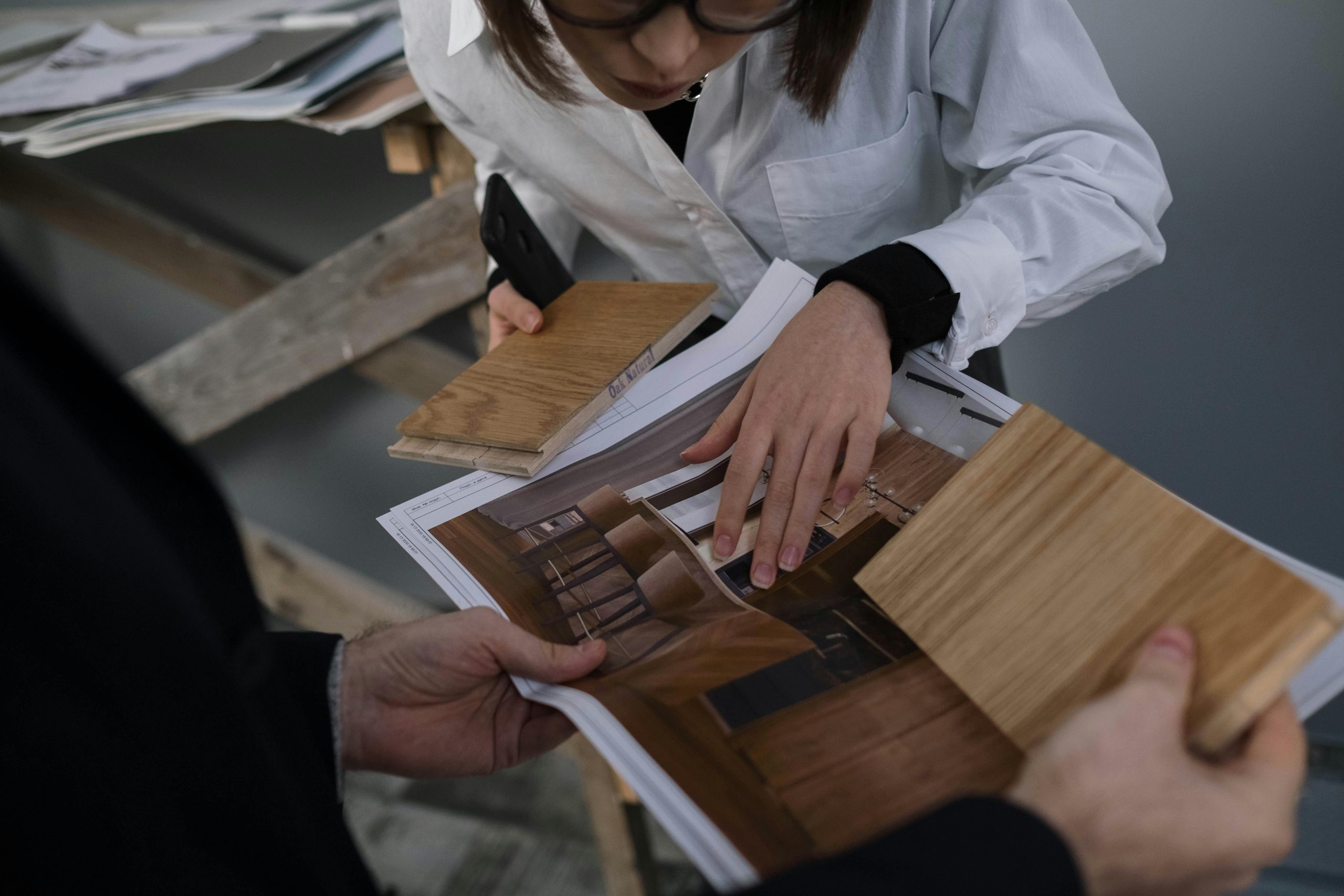 Two people collaborate on a design, looking over samples and a rendering of their space featuring the custom design.