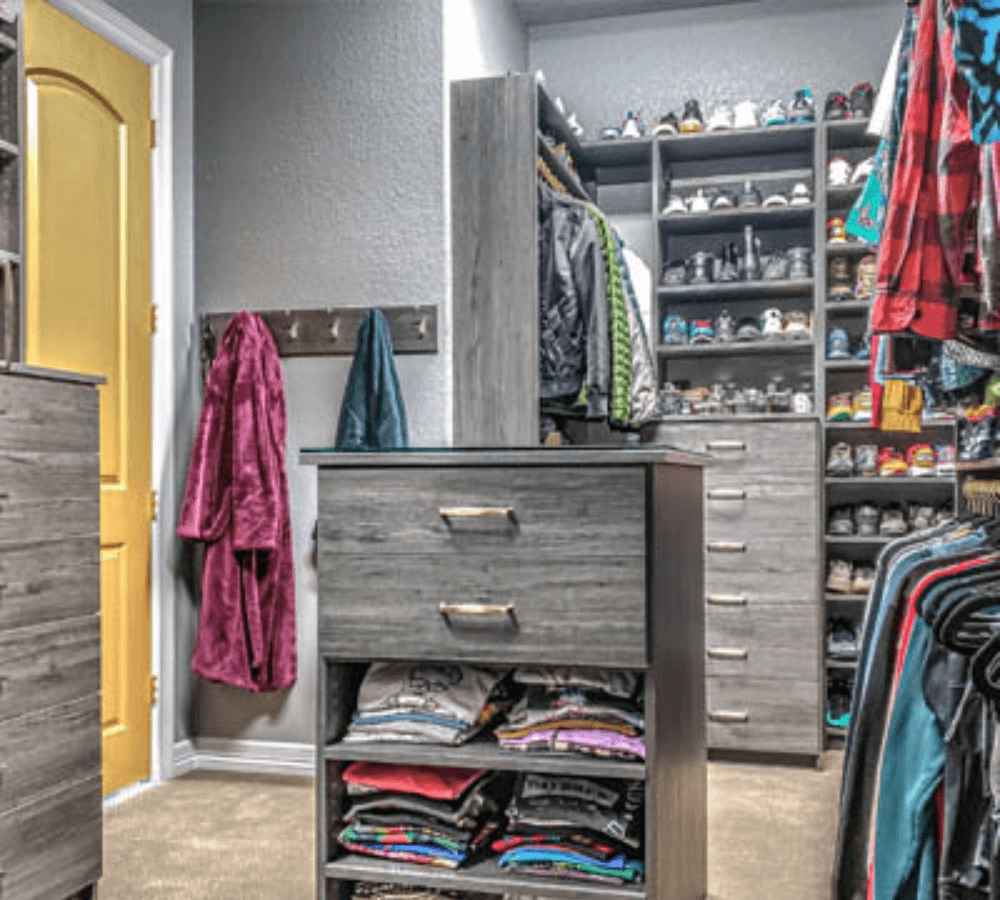 A full closet in a grey room with an island in the middle.