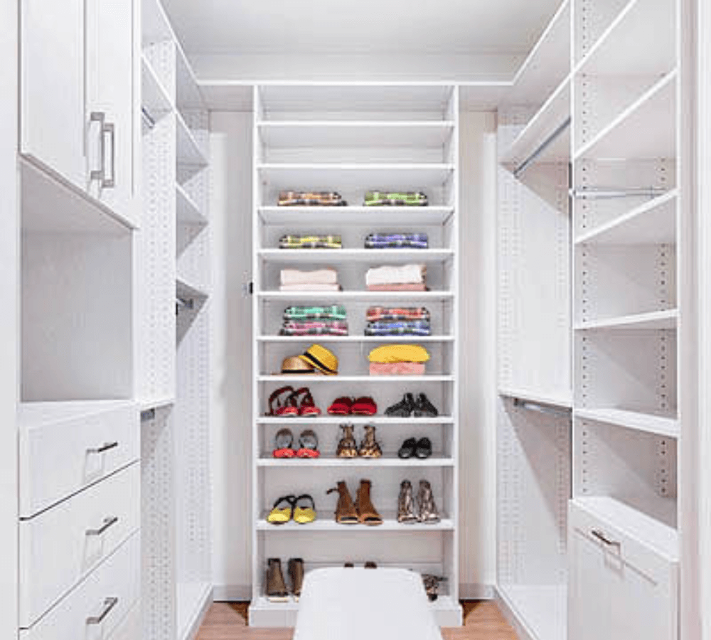 An all-white closet with cabinents and shelving.