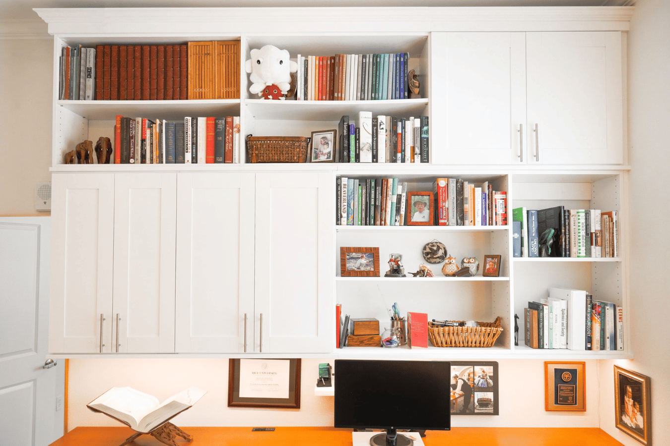 Custom home office storage featuring white cabinets, open shelving, and a built-in desk